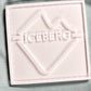 A white rubber "ICEBERG" patch with an abstract iceberg design is sewn onto the light mint 100% polyester fabric of the Iceberg ICE25MBM01 Medium Boardshort, echoing classic brand swim trunk details.