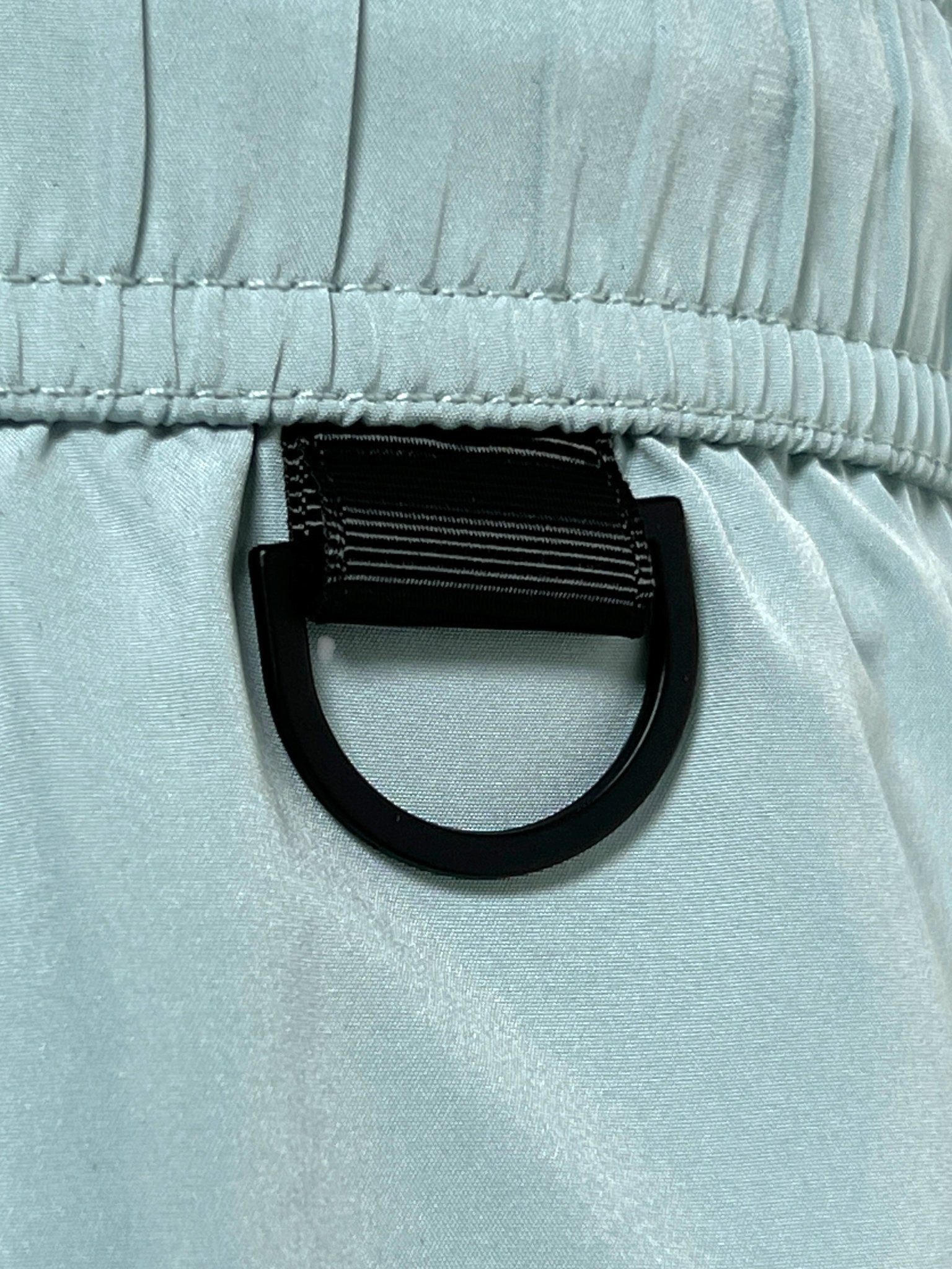 Close-up of a black D-ring on the ICEBERG ICE25MBM01 Medium Boardshort in mint, featuring imported 100% polyester, detailed stitching, and gathered elastic at the top.