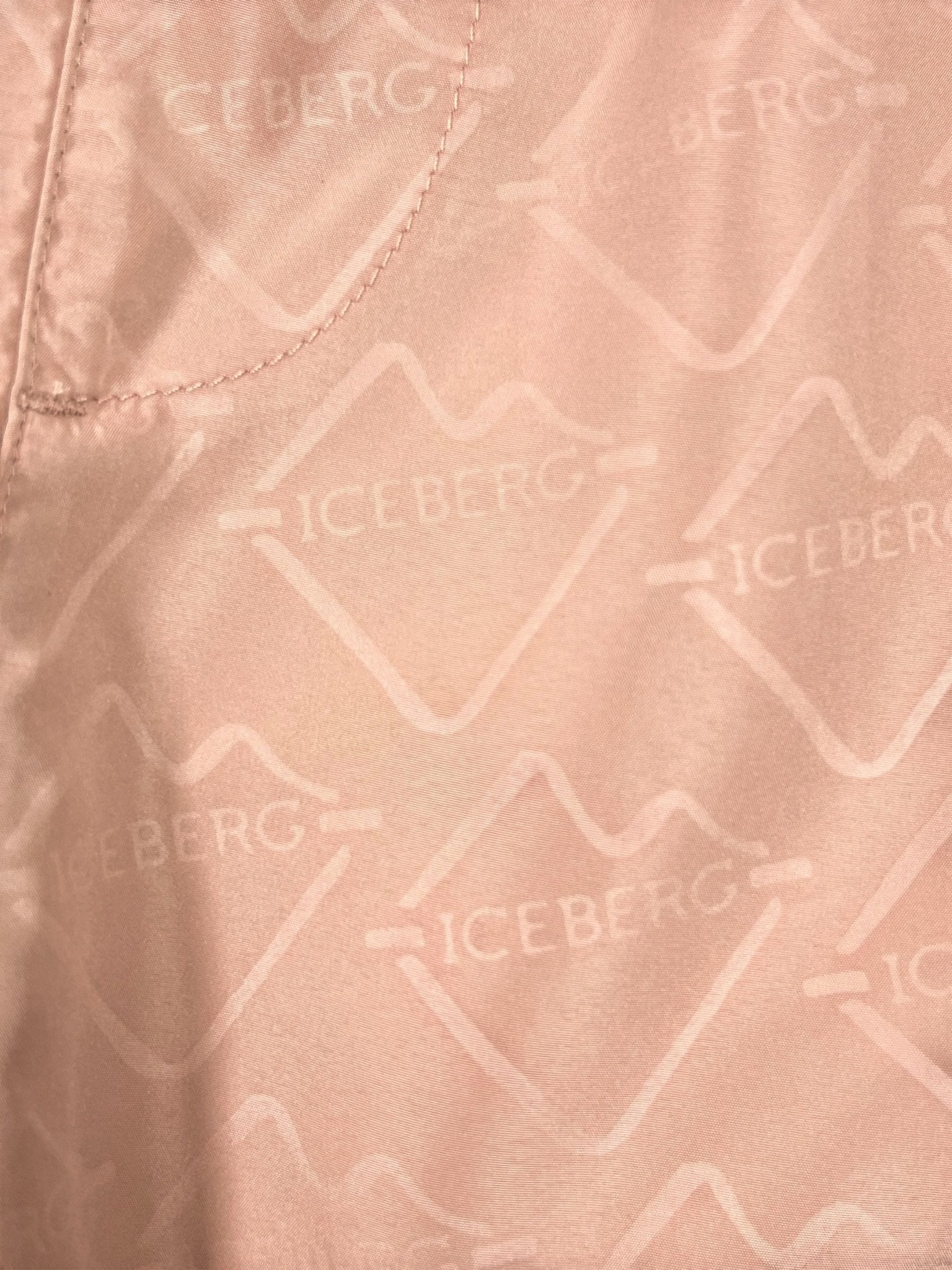 Close-up of ICEBERG ICE25MBS05 Short Boardshort Blush: light pink polyester with repeated "ICEBERG" logos and visible seam stitching—ideal for chic swim trunk style.