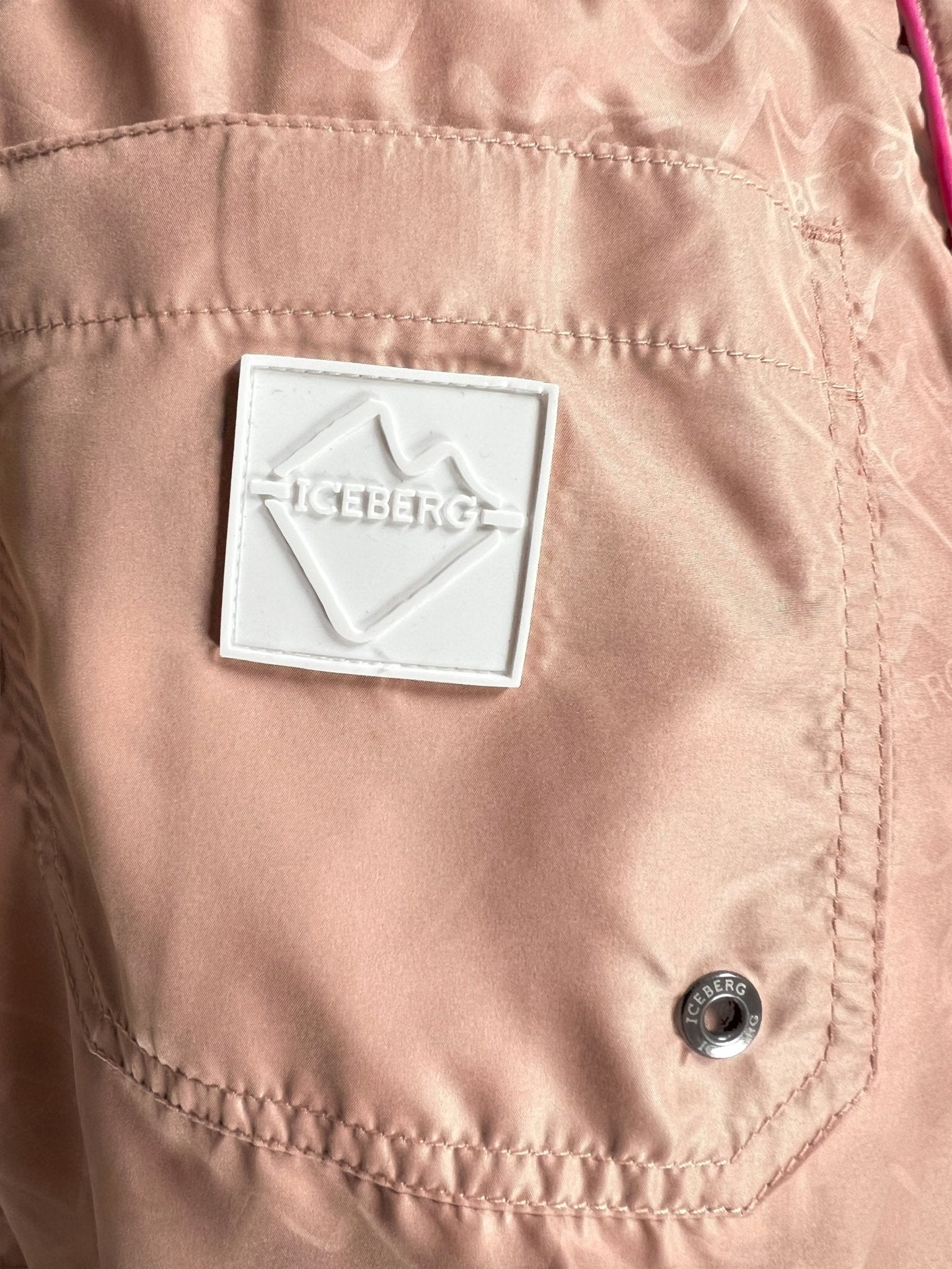 Close-up of the blush Iceberg ICE25MBS05 Short Boardshort’s light pink polyester pocket, featuring a white "ICEBERG" patch and a branded snap button.