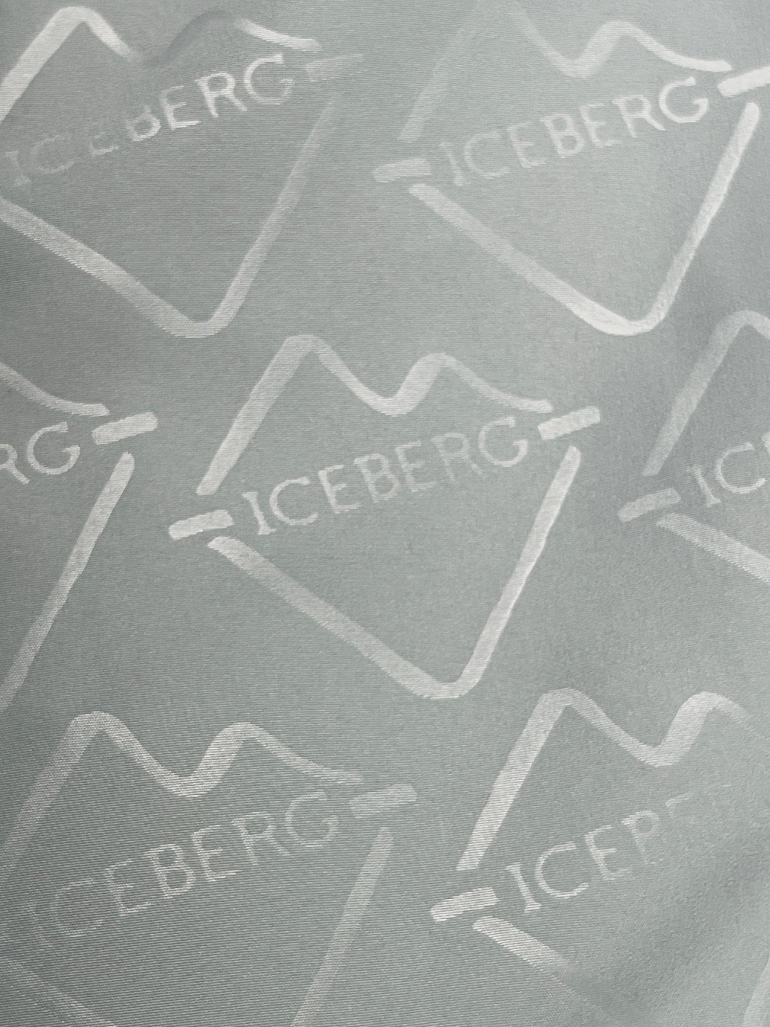 Close-up of mint polyester fabric with repeating white "ICEBERG" logos and iceberg outlines—featured in ICEBERG's ICE25MBS05 Short Boardshort Mint.