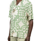 A man wearing the INIMIGO Inimigo ISH3525 Palm Shirt Green, featuring green and white palm designs, paired with light-colored shorts. This versatile button-up shirt effortlessly captures a laid-back vibe.