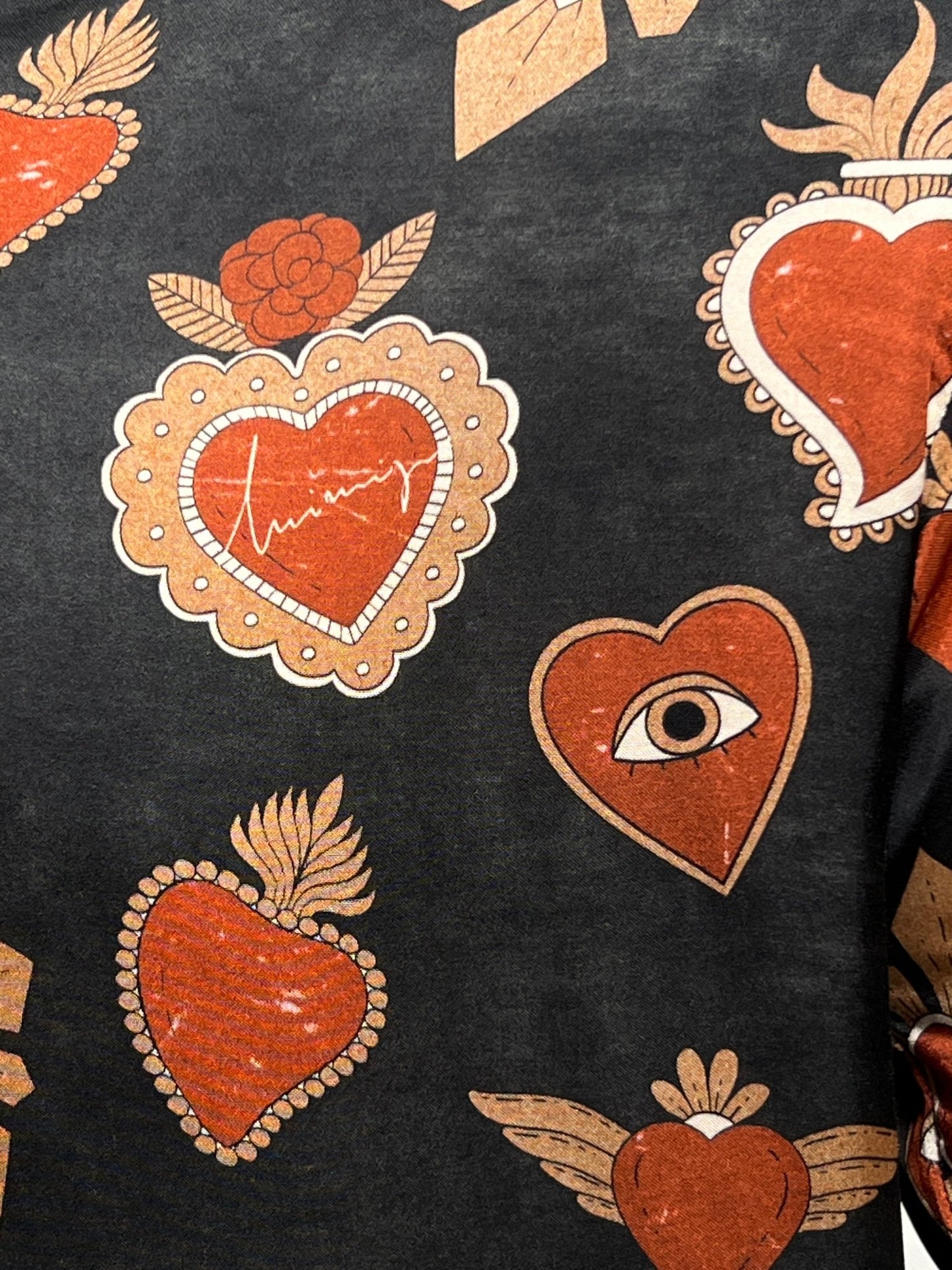 A versatile men's shirt, the INIMIGO ISH3527 MEXICAN HEARTS SHIRT BLACK by INIMIGO, featuring a fabric pattern of red hearts, one with an eye, and floral designs with gold accents on a black background.