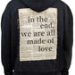 The Inimigo Letter Oversized Hoodie Dk Black by INIMIGO is an oversized black hoodie crafted from organic cotton, featuring the text "In the end, we are all made of love" on the back against a newspaper-style background.