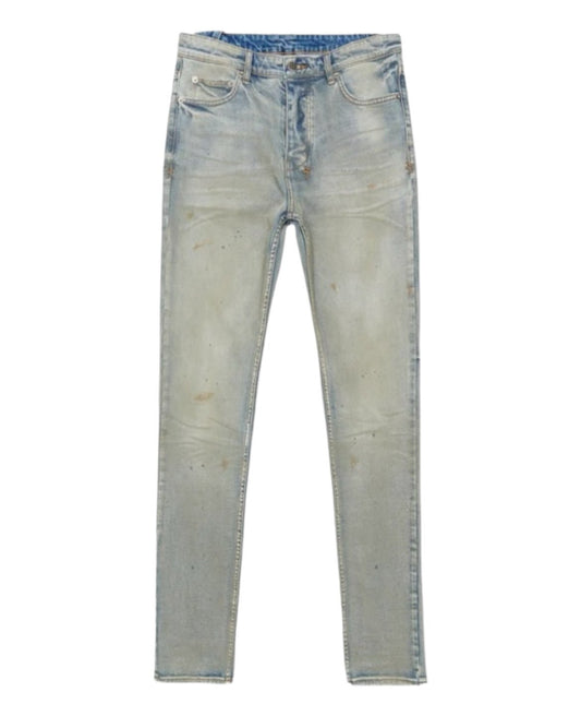 These KSUBI CHITCH MECHANIK DENIM jeans from KSUBI come in light blue stretch denim, showcasing a worn, distressed look with subtle fading and small scattered stains. Designed with a slim tapered fit, they offer both comfort and style for an effortlessly cool vibe.