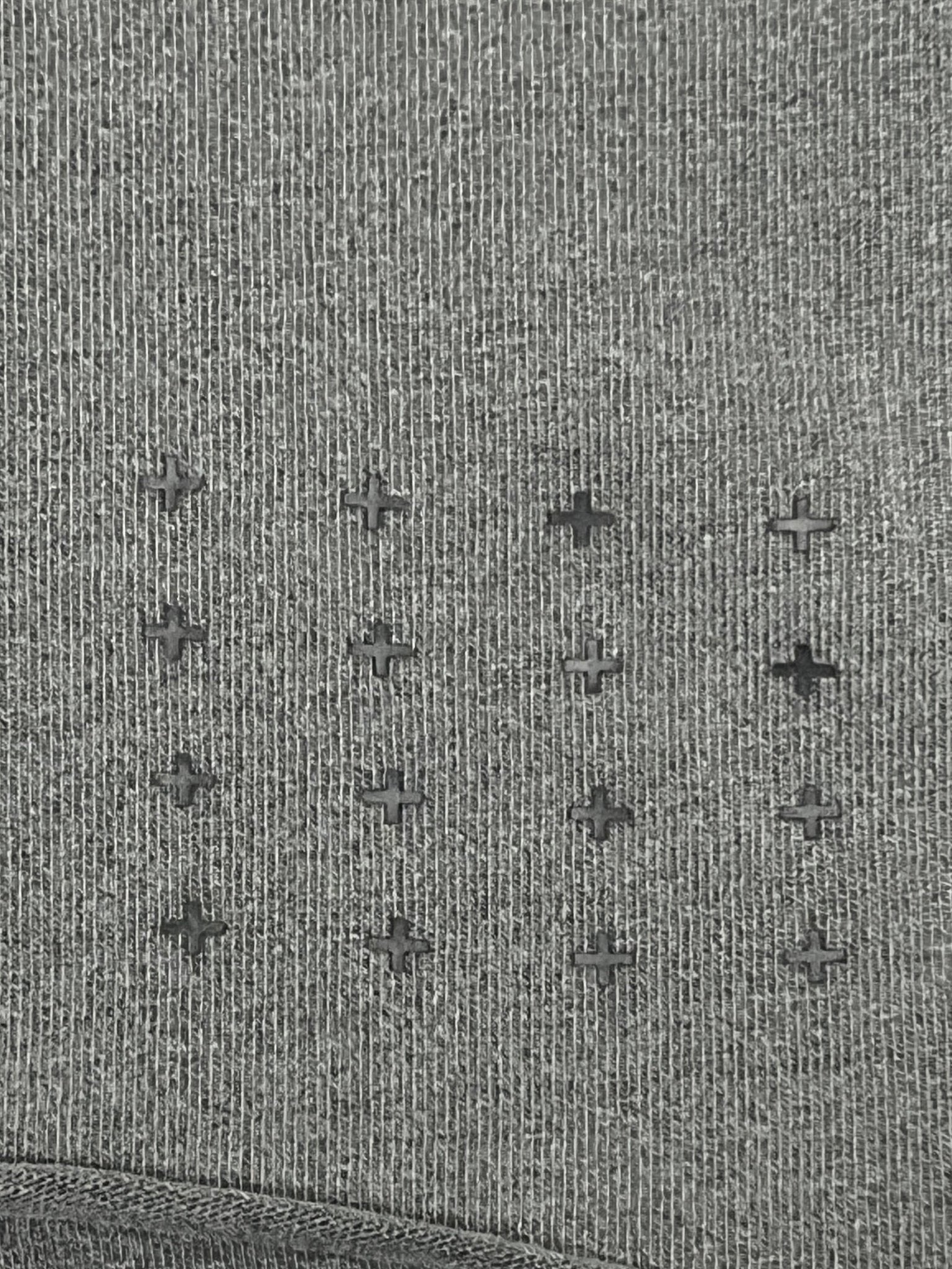 Gray fabric with a grid of tiny, even, plus-shaped perforations, resembling the vintage Ksubi Fuego Ekcess SS Tee in Faded Black from KSUBI.