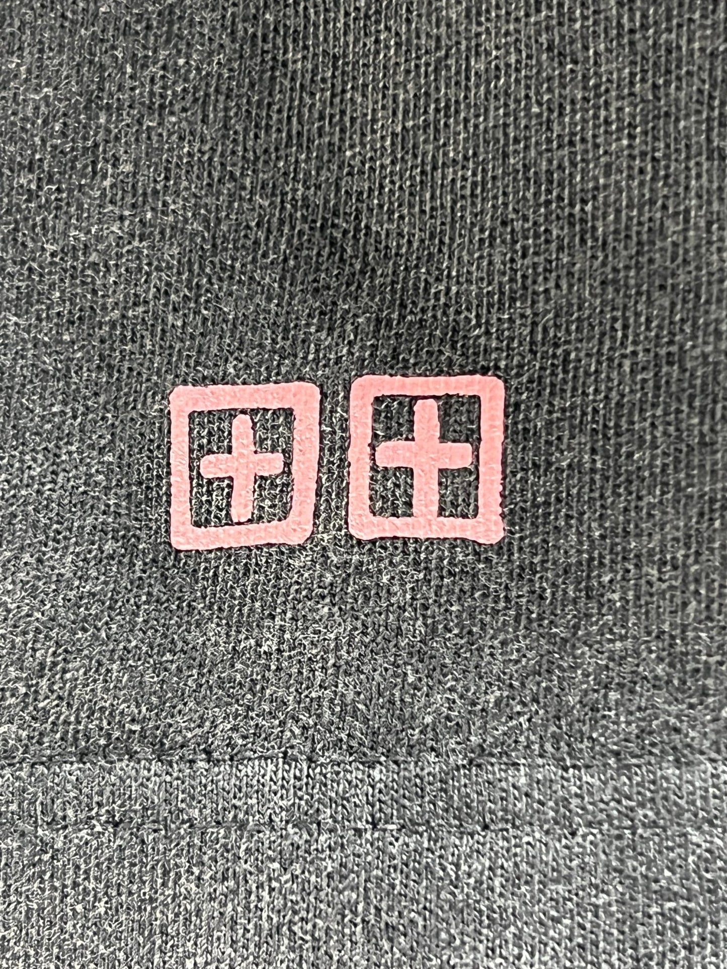 A close-up of the fabric from the Ksubi Graff Rose Kash Tee Acid Grey, featuring two pink square symbols with cross designs subtly nodding to the KSUBI logo rose.