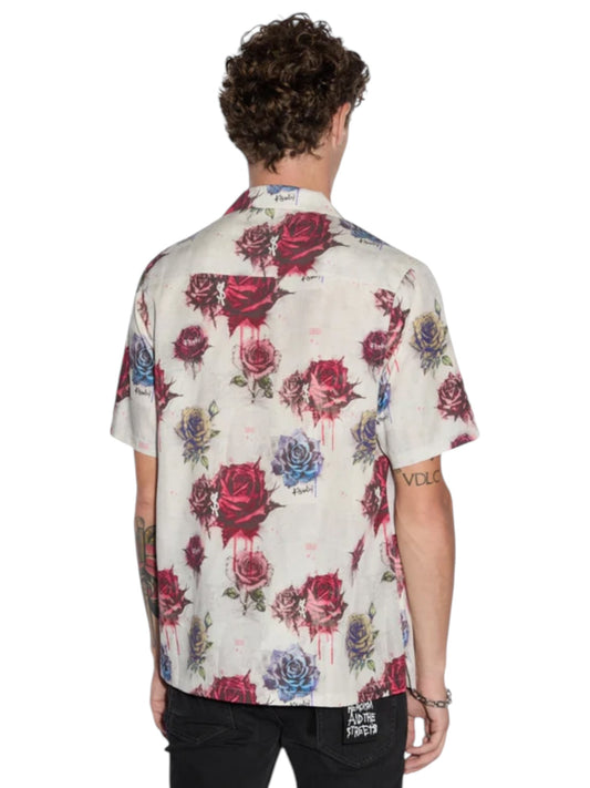 The person is wearing a Ksubi Graff Rose Resort Shirt Multi, made from breathable Tencel, featuring a bold red and blue rose pattern. They stand with their back to the camera, exemplifying KSUBI's signature style.