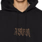 Someone wearing the Ksubi Kingdom Biggie Hoodie in jet black by KSUBI, featuring oversized fit and "KSUBI" embroidered in stylized letters on the front.
