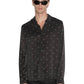 A person wearing sunglasses, a stylish Ksubi Polka Plus Ls Shirt Black—a KSUBI long sleeve button-down—and black pants stands against a plain background.