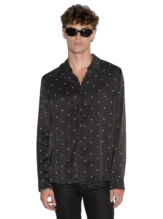 A person with curly hair wearing black sunglasses, a KSUBI Polka Plus LS Shirt Black with white polka dots, and black pants stands facing forward against a white background.