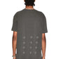 A person with braided hair is seen from the back, wearing a Ksubi Skull Biggie Ss Tee in Faded Black by KSUBI, featuring cross patterns, paired with premium cotton light jeans.