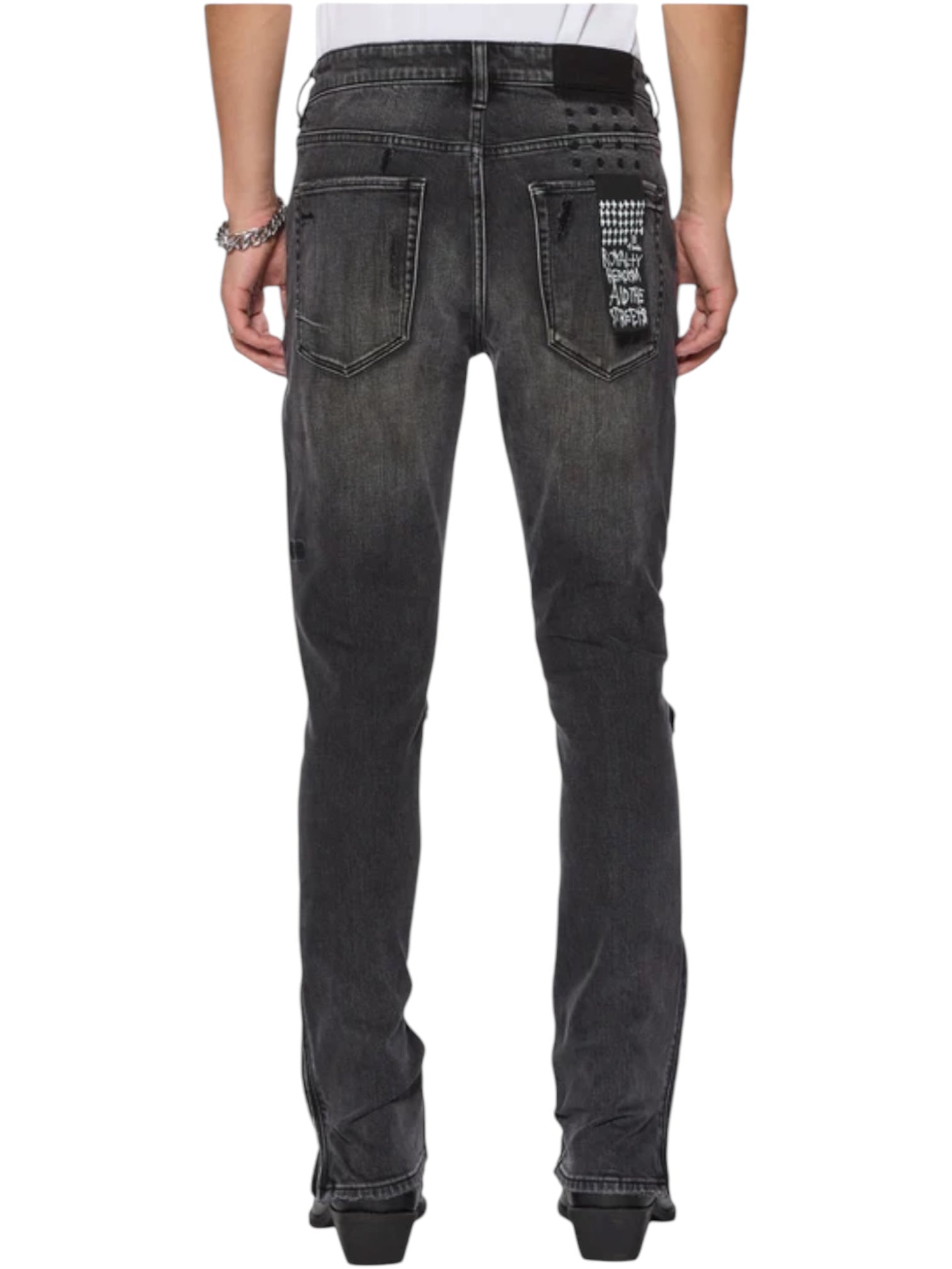 A person is seen from the back wearing KSUBI’s Van Winkle Torqued Chamber Black skinny jeans, featuring faded black denim, patch details on the right pocket, and visible stitching for a modern look.