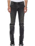 A person wearing KSUBI Van Winkle Torqued Chamber Black jeans with visible knee seams and black square-toe boots, standing against a white background. These jeans provide premium comfort stretch for all-day wear.