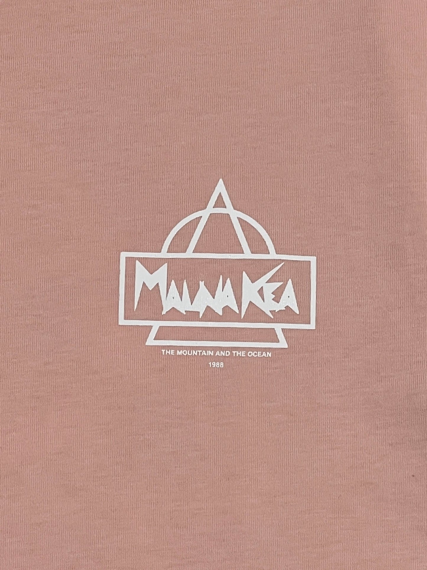 A pink, 100% cotton MAUNA-KEA MKE100-04 HERITAGE TEE W SCREEN PRINT PINK from MAUNA-KEA featuring a white outline of a triangular mountain, the text "Mauna Kea," and smaller print saying "The Mountain and The Ocean 1988.