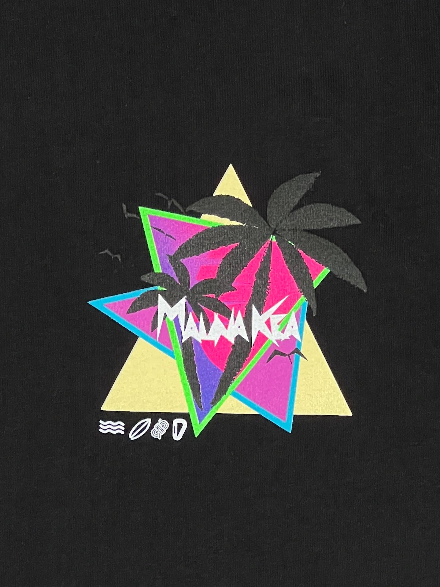 Introducing the Mauna-Kea Mku100-P999 Sunset Palms Tee Blk by MAUNA-KEA—a chic graphic tee featuring a retro design with overlapping triangles, vibrant palm trees, and bold "MADARCA" text on a sleek black background. It is adorned with small wave, leaf, and cup icons for added flair. Crafted from 100% cotton to ensure ultimate comfort.