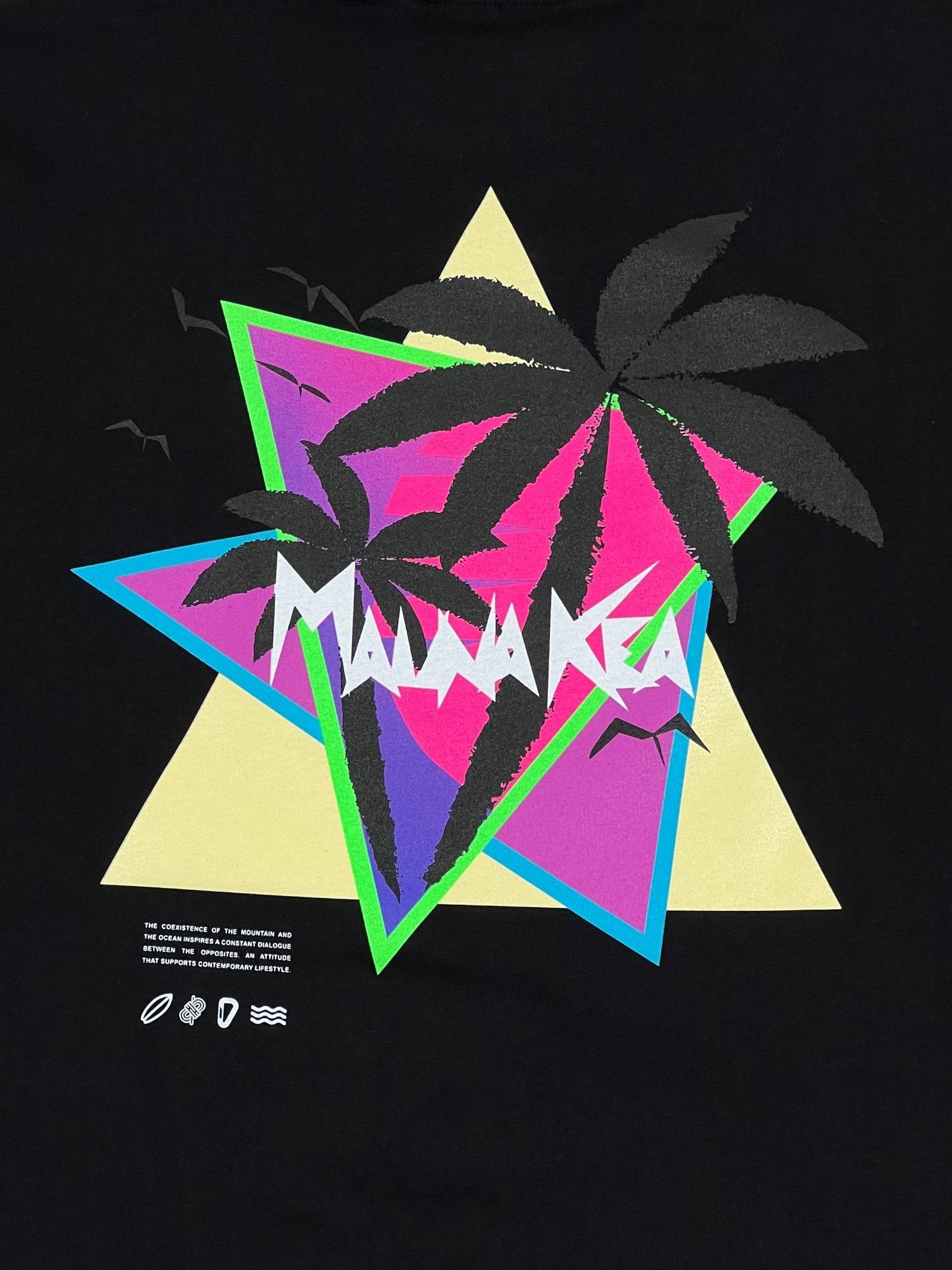 The Mauna-Kea Mku100-P999 Sunset Palms Tee Blk by MAUNA-KEA showcases an eye-catching design with layered geometric shapes in pink, yellow, and teal, featuring stylized palm trees and the word "Manaka" boldly displayed.