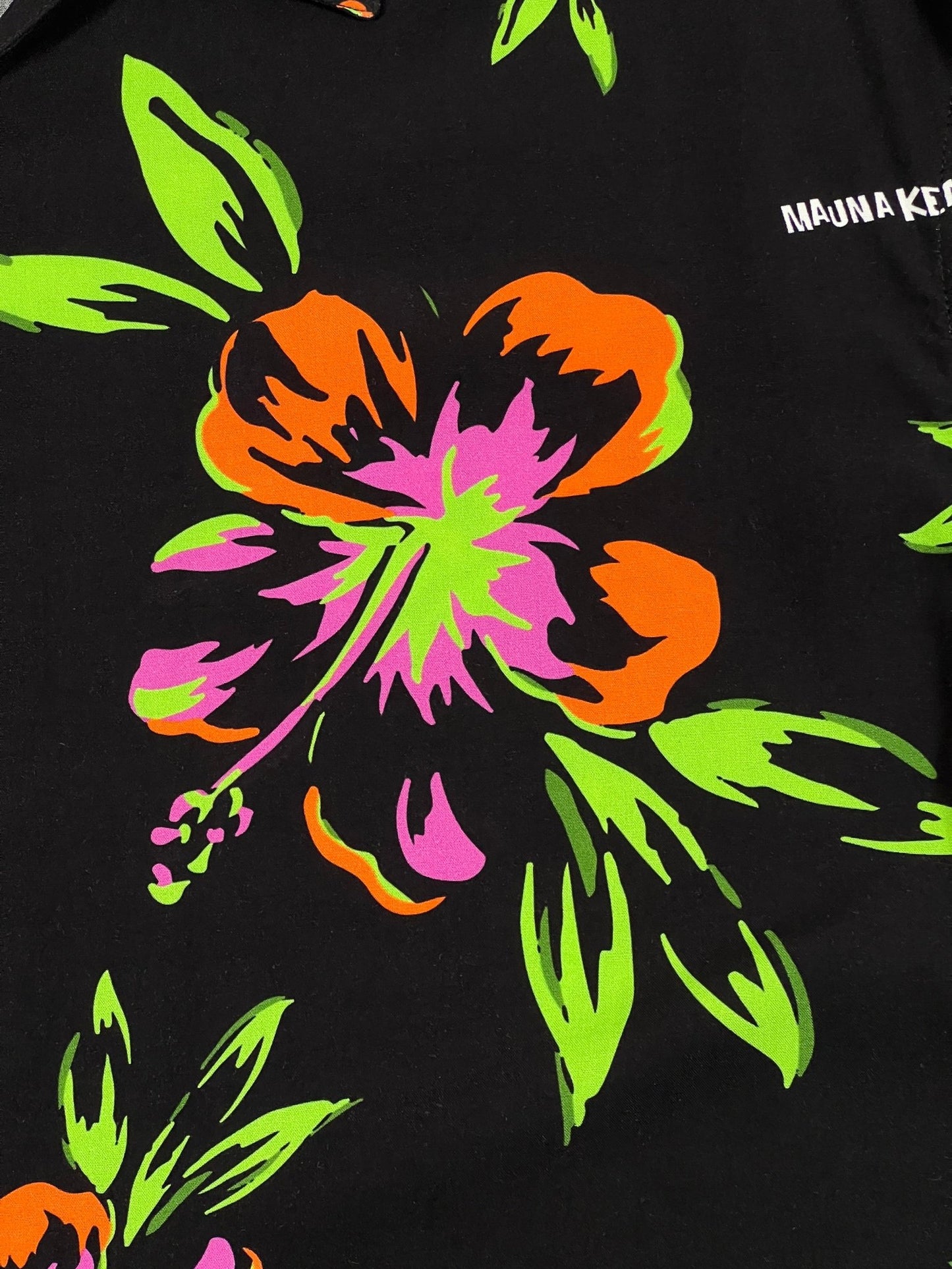 A vibrant graphic roses print with neon green and orange colors on a black fabric, featuring text "MAUNA-KEA" on top.