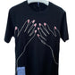 Display of a Mcq By Mcqueen 647244Rst87 T-Shirt in darkest black featuring a two-hand illustration with pink nails. A small tag subtly adorns the embroidered graphic design, enhancing the visual appeal on the hanger. Brand: MCQ BY MCQUEEN.