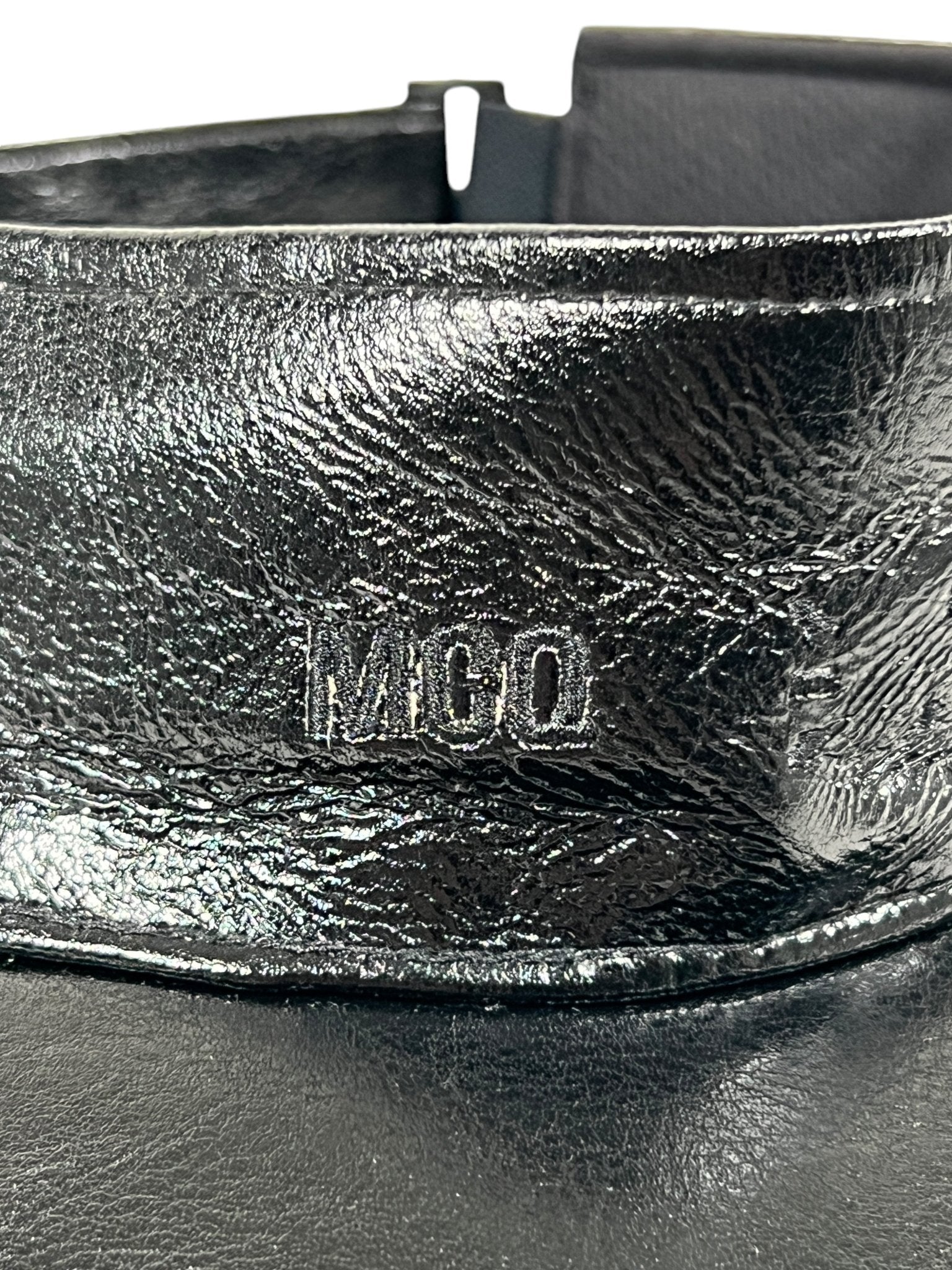 A close-up of the Mcq By Mcqueen 692287Rgc96 Handsy Visor Black cap, showcasing its black leather with a shiny texture and embossed "MCO" letters.