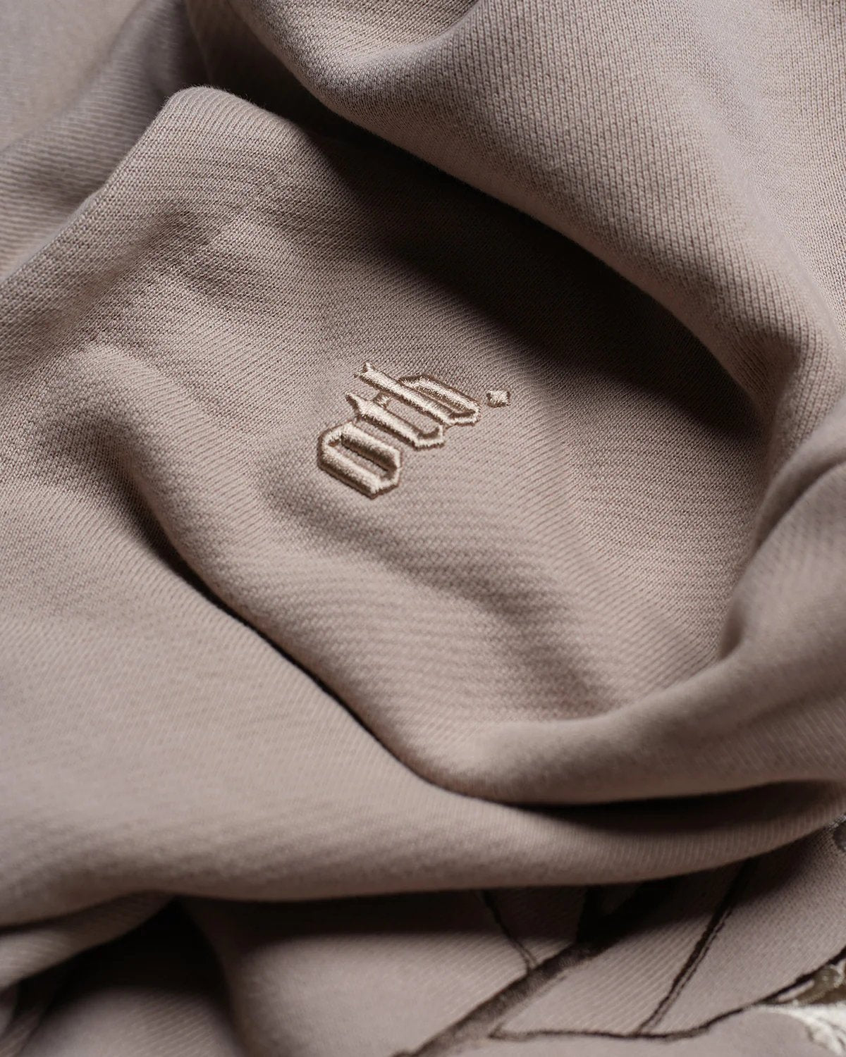 Detailed view of the heavyweight cotton hoodie material in a summer hue, showcasing the embroidered letters "owh" in coordinating thread. This is the Only The Blind OTB-H1033 Ogiku Embroidered Hood by ONLY THE BLIND.