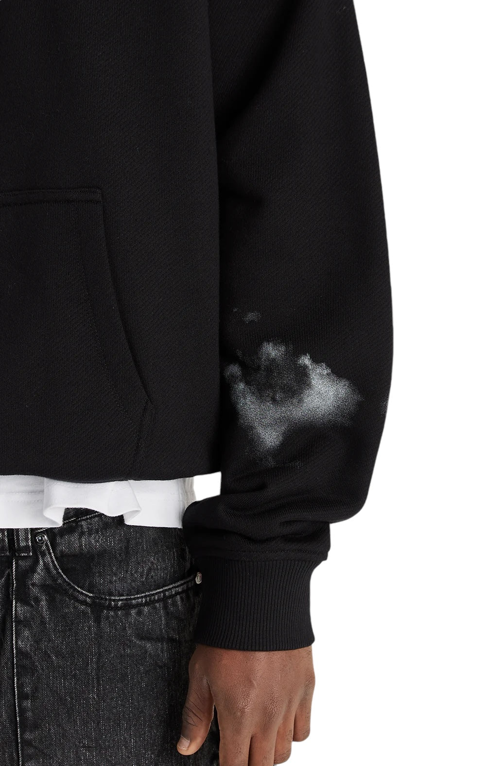 A person in an ONLY THE BLIND OTB-H1355 Midnight Hawk Hoodie in black, marked by a white paint stain on the sleeve, wears black jeans and stands against a white background.