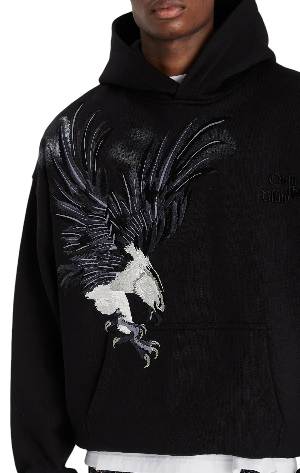 The person sports an Only The Blind OTB-H1355 Midnight Hawk Hoodie Blk from ONLY THE BLIND, featuring intricate embroidery of a majestic eagle.