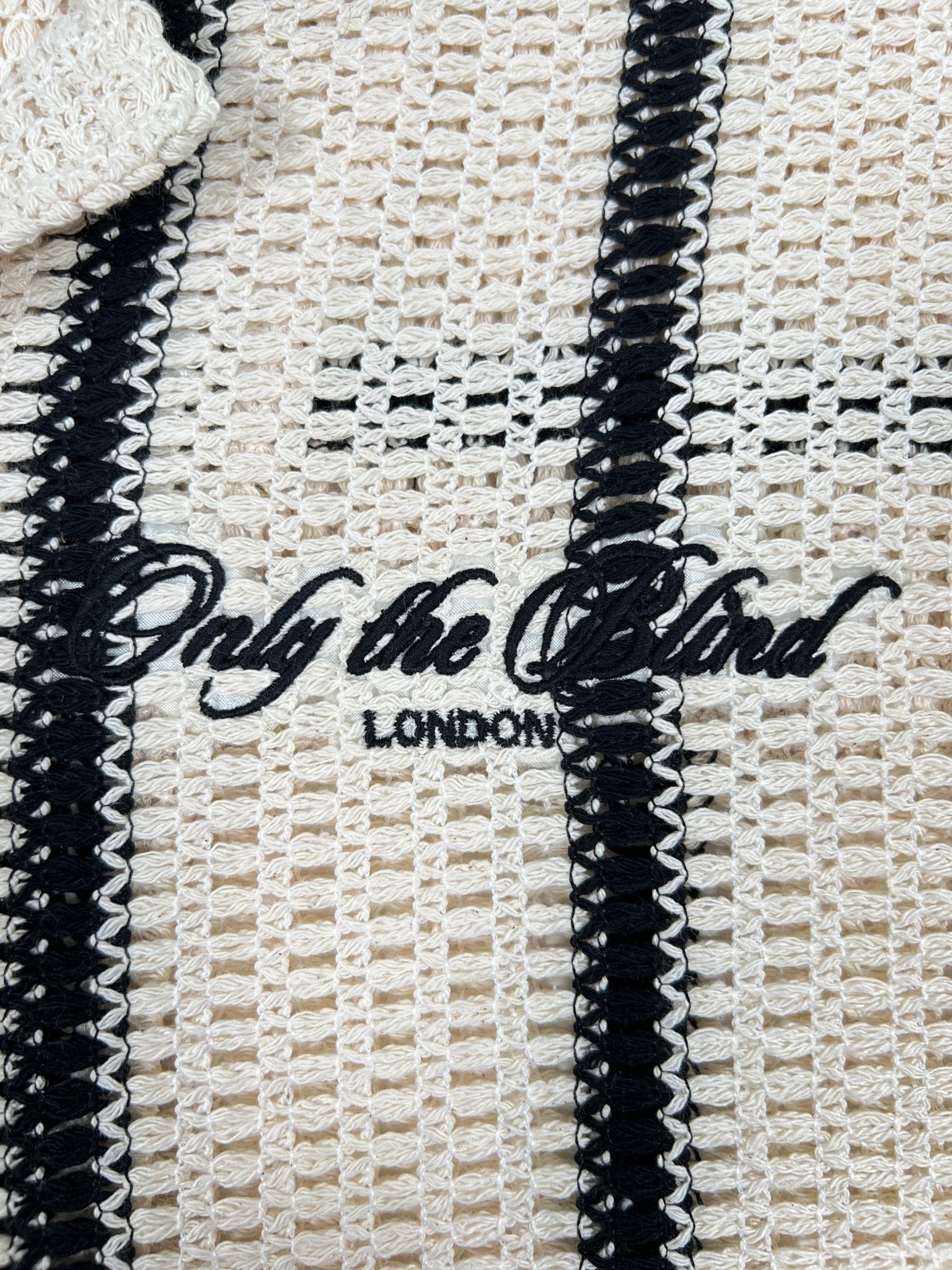 The Only The Blind OTB-SH1520 Desert Stripe Crochet Shirt showcases beige and black stripes with "Only The Blind LONDON" embroidered, offering a chic and modern look.