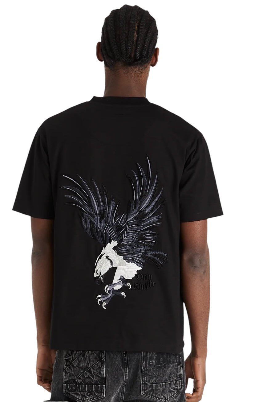 A person is wearing the ONLY THE BLIND Midnight Hawk T-shirt (model OTB-T1357) in black, featuring a striking large eagle design on the back, as showcased from behind.