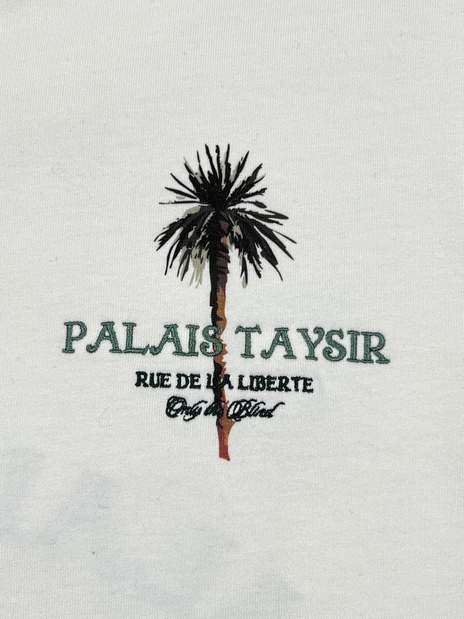 The ONLY THE BLIND OTB-T1486 Palais Taysir T-shirt Beige features a palm tree graphic and "PALAIS TAYSIR RUE DE LA LIBERTE Only the Finest" text on organic cotton with light fabric.