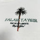 The ONLY THE BLIND OTB-T1486 Palais Taysir T-shirt in beige is made from organic cotton and features a white embroidered palm tree graphic with “PALAIS TAYSIR RUE DE LA LIBERTE” text in green and black.