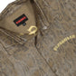Close-up of the brown Pleasures Anaconda Overshirt Brw, highlighting its textured pattern with "PLEASURES" in yellow on the chest and a small collar tag.