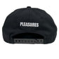 The PLEASURES BAKED LOGO SNAPBACK BLACK is displayed from the back, showcasing the word "PLEASURES" embroidered in white thread. This cap, crafted from durable Polyester and Nylon, includes an adjustable plastic strap for a perfect fit.