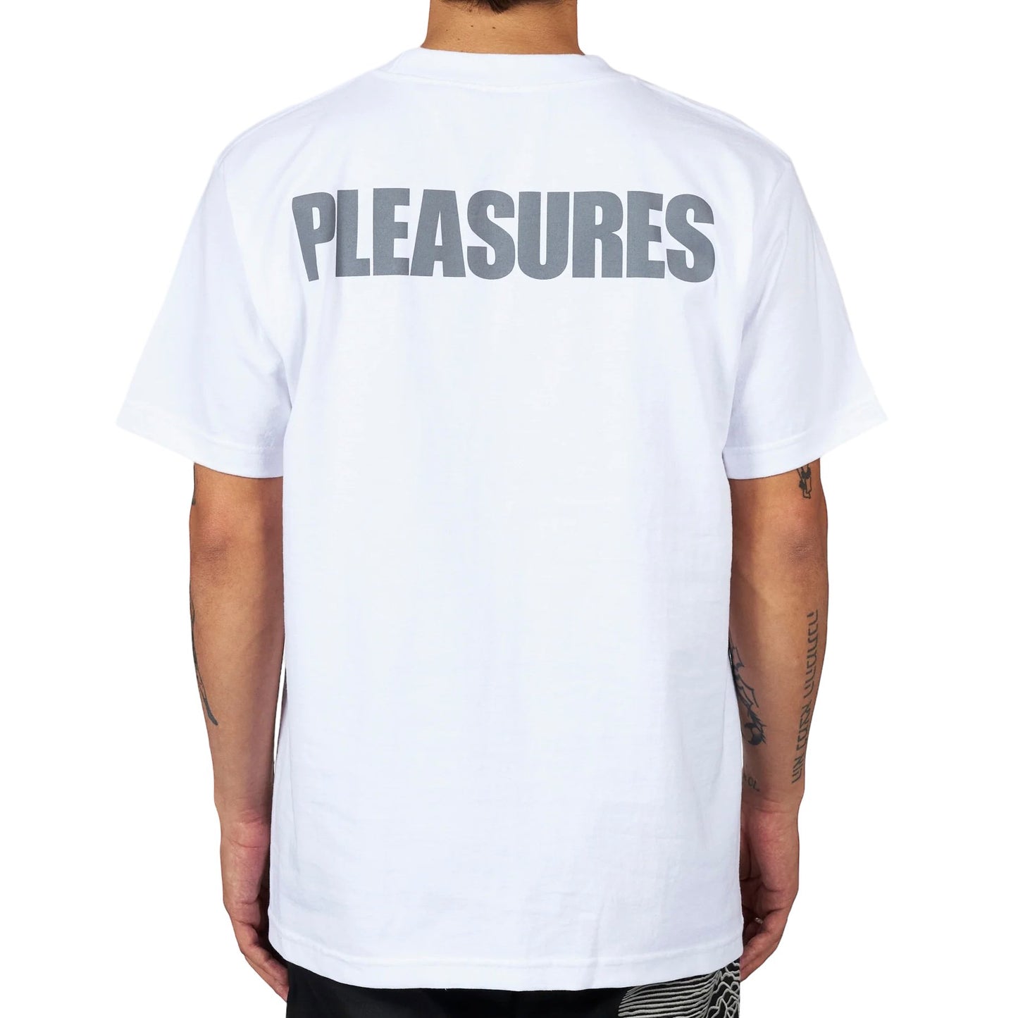 Man wearing a PLEASURES BROKEN IN T-SHIRT WHT with the word "pleasures" screen printed on the back, featuring a Joy Division collaboration.