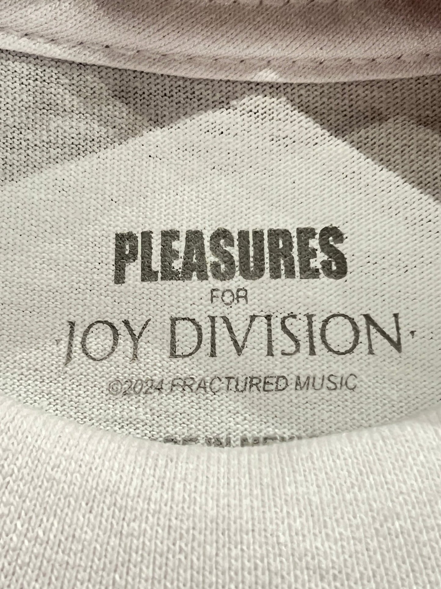 A PLEASURES BROKEN IN T-SHIRT WHT with the text "pleasures for Joy Division collaboration ©️2014 fractured music.