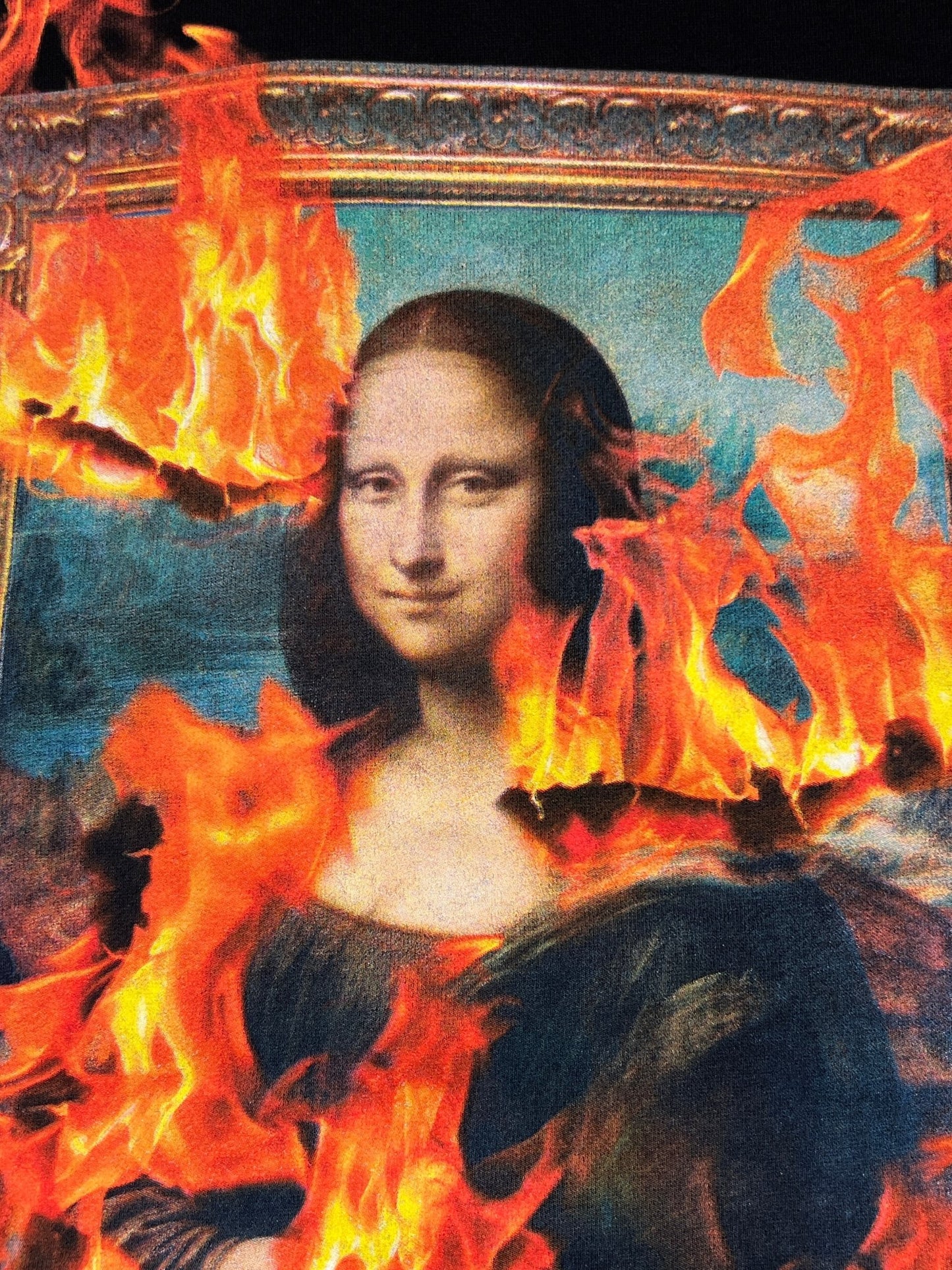 The Pleasures Burn Again Hoodie by PLEASURES features the Mona Lisa painting, screen printed with vivid orange flames on a luxurious black cotton and polyester blend.