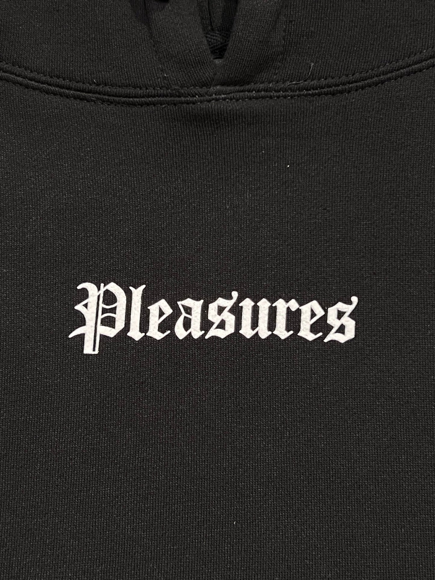 The Pleasures Burn Again Hoodie Black by PLEASURES features black cotton fabric with "Pleasures" in a white Gothic-style screen print.