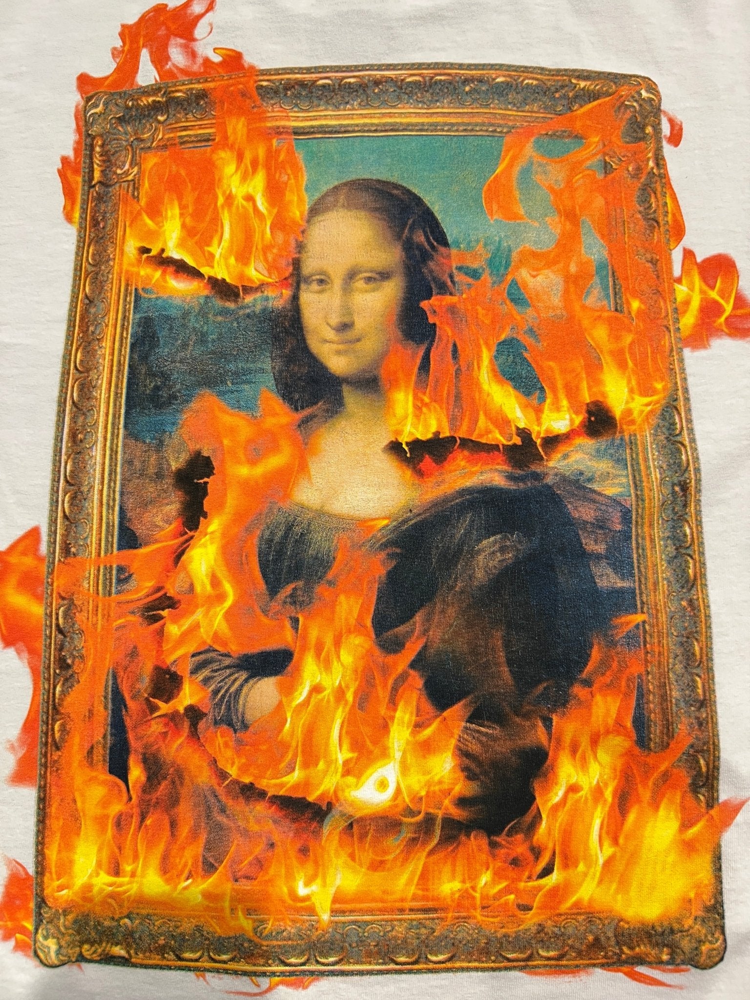The PLEASURES Burn Again T-shirt White features a printed Mona Lisa surrounded by digital flames, creating a "on fire" effect. Made from cotton with a boxy fit for comfort and modern style.