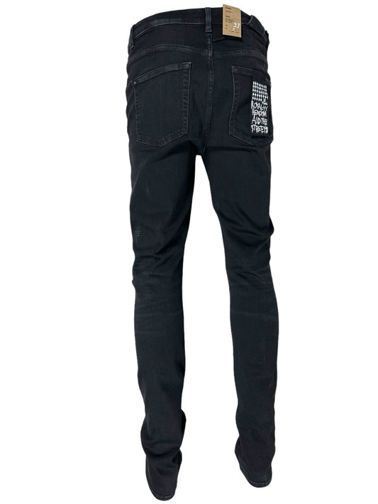 The KSUBI Ksubi Chitch Apex Krystal Black jeans showcase a back view of slim straight black denim with a white embroidered text design on the right back pocket, subtly enhanced by crystal details. A tag attached to the waistband completes this stylish piece.