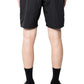 A person shown from the back wears a black shirt, PLEASURES Pleasures Crush Hiking Shorts Black with an elasticized waistband, black crew socks, and black athletic shoes with orange accents.