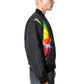 A person in a black cap, Pleasures Daft Club Reversible Bomber Black by PLEASURES with sublimated graphics and sleeve lettering, and blue jeans stands facing sideways.