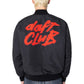 Person seen from behind wearing the PLEASURES Daft Club Reversible Bomber Black, a padded Taslan nylon jacket with "daft CLUB" in red stylized graphics on the back.