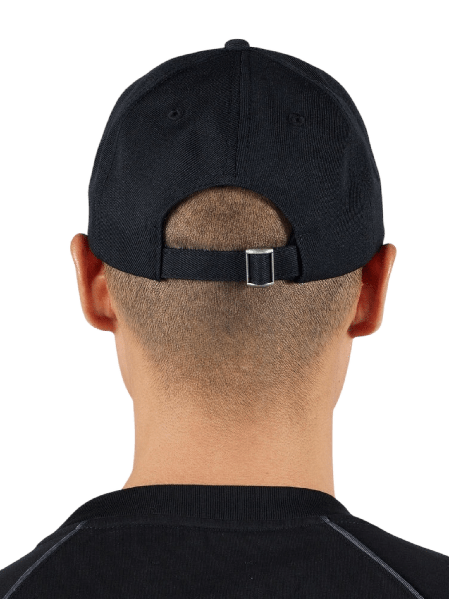 A person with short hair wears a backwards Pleasures Daniele Cap Black, showcasing its adjustable fit and an embroidered boar logo that marks the exclusive PLEASURES x Iuter collaboration.