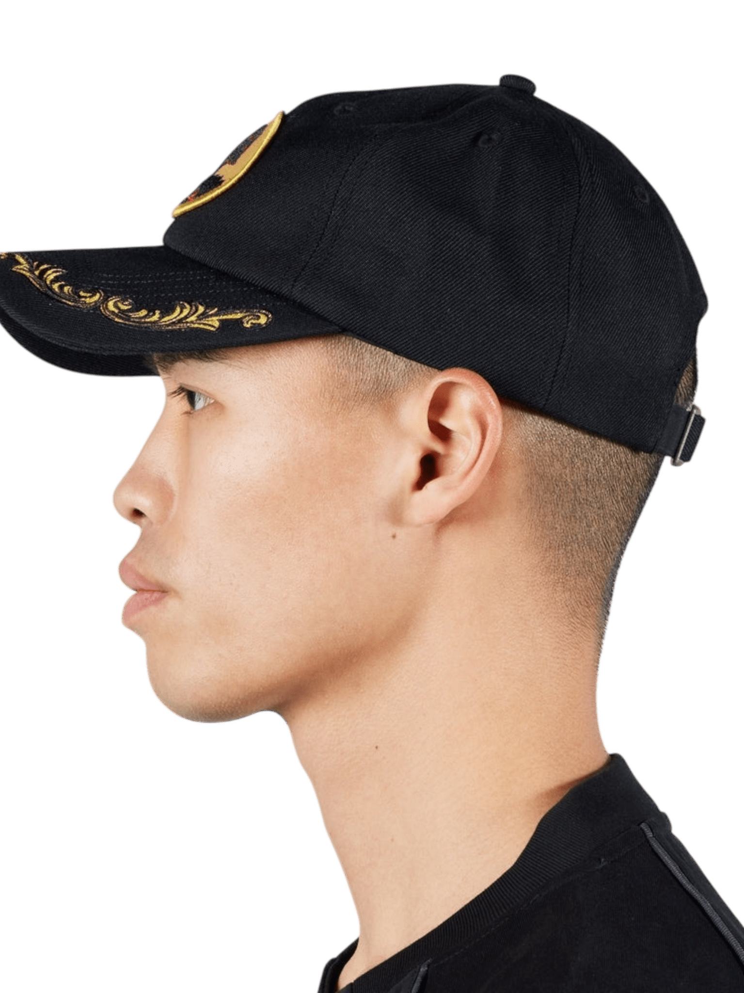 A person in profile is wearing a Pleasures Daniele Cap Black featuring gold embroidery and an embroidered boar logo against a plain background. The PLEASURES cap offers an adjustable fit for comfort and style.
