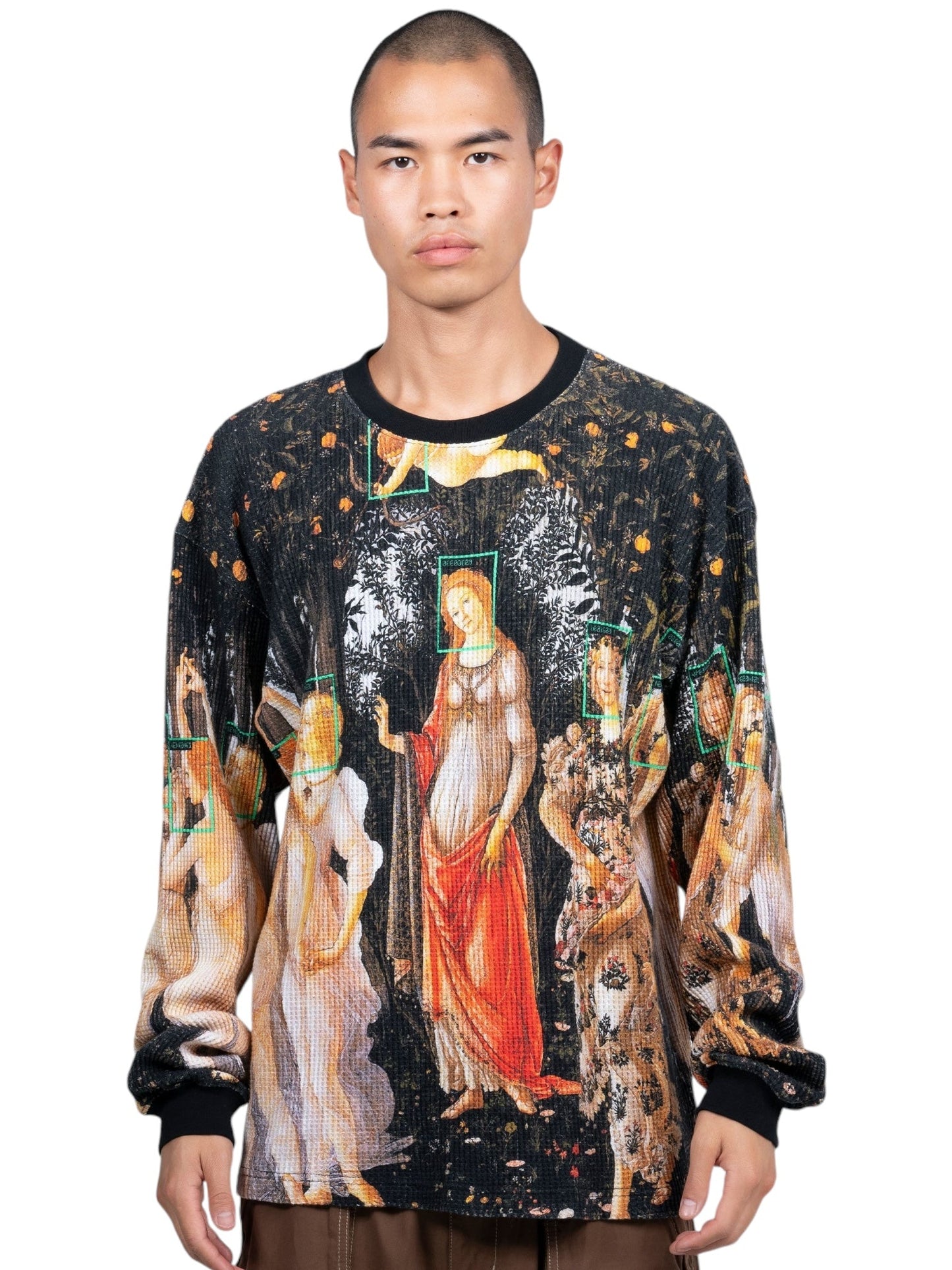 The individual is wearing the Pleasures Facial Thermal L/S T-shirt in black from PLEASURES, made from 100% cotton, featuring a Renaissance art print. The digital printed graphic stands out against the black background.