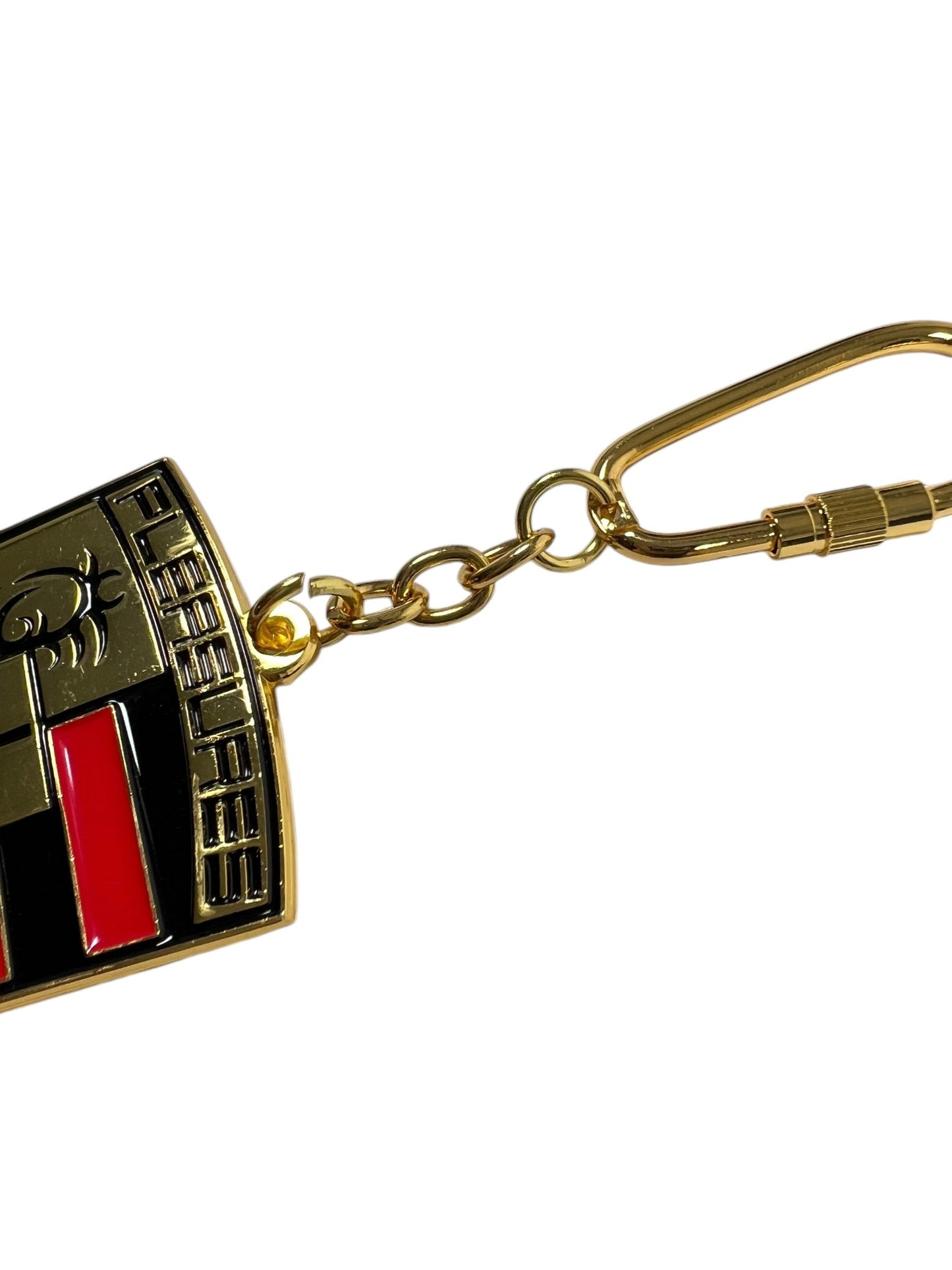 A close-up of the Pleasures Fast Life Keychain Multi from PLEASURES displays a metallic emblem with embossed designs, highlighted by red and black accents, offering small pleasures for the discerning eye.