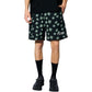 A person wears Pleasures Floral Seersucker Shorts Black by PLEASURES, featuring green clover patterns and an embroidered logo, paired with a black T-shirt, socks, and shoes, styled on a crisp white background.