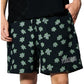 Someone wearing the PLEASURES Floral Seersucker Shorts Black, featuring a green floral pattern and "PLEASURES" embroidered in white on the left leg.