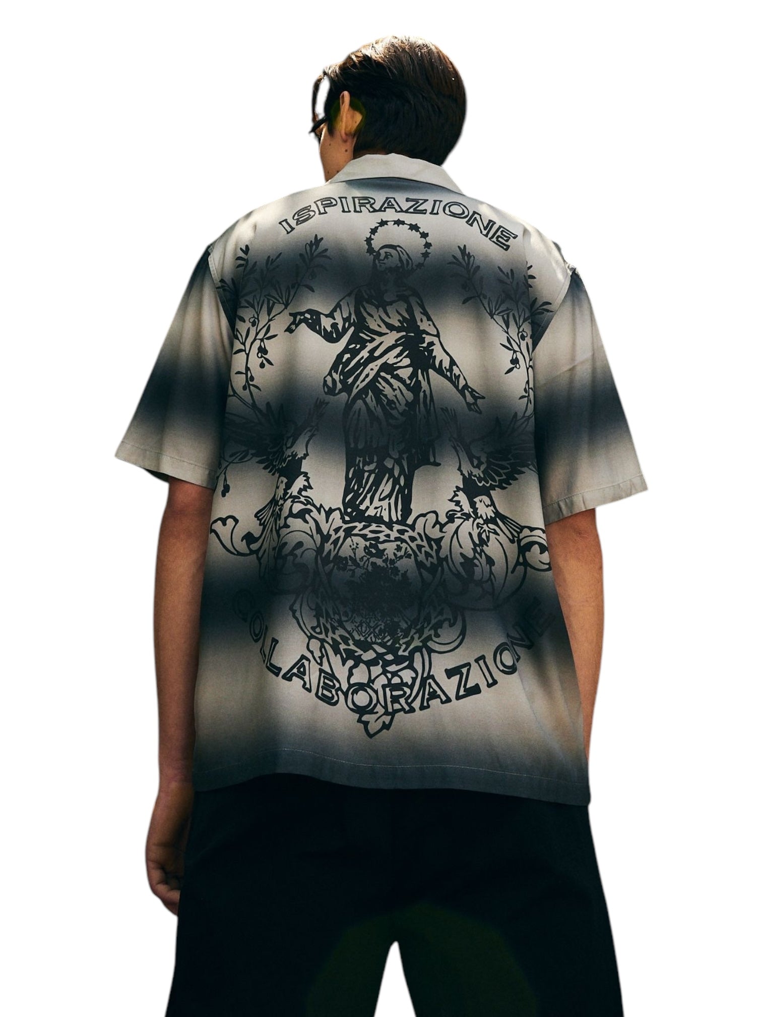 A person wearing the Pleasures Giovanni BUTTON UP SILVER from PLEASURES, a camp collar grayscale gradient shirt made of luxurious viscose challis, featuring an artistic design and Italian text on the back. This stylish piece is proudly made in Italy.