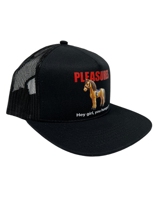 The PLEASURES HORSE TRUCKER BLACK hat from PLEASURES is crafted from durable nylon and polyester. It features "PLEASURES" in red text above an image of a horse, with the cheeky phrase "Hey girl, you hungry?" displayed below the horse.
